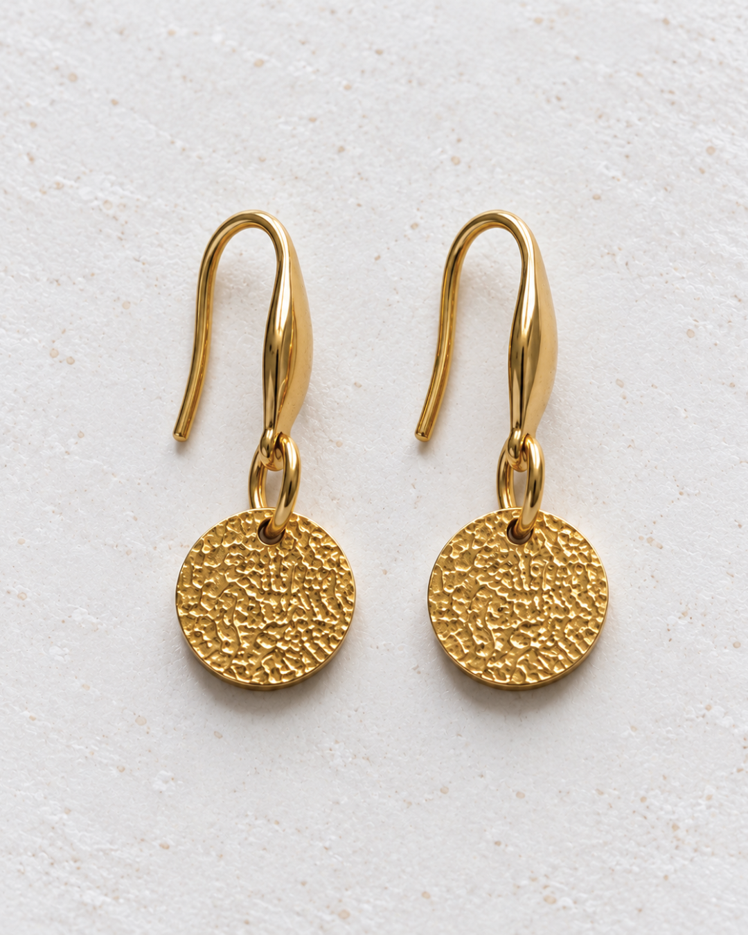 Pendientes Halo de Hanalima: disco dorado martillado con gancho de acero inoxidable, packshot frontal